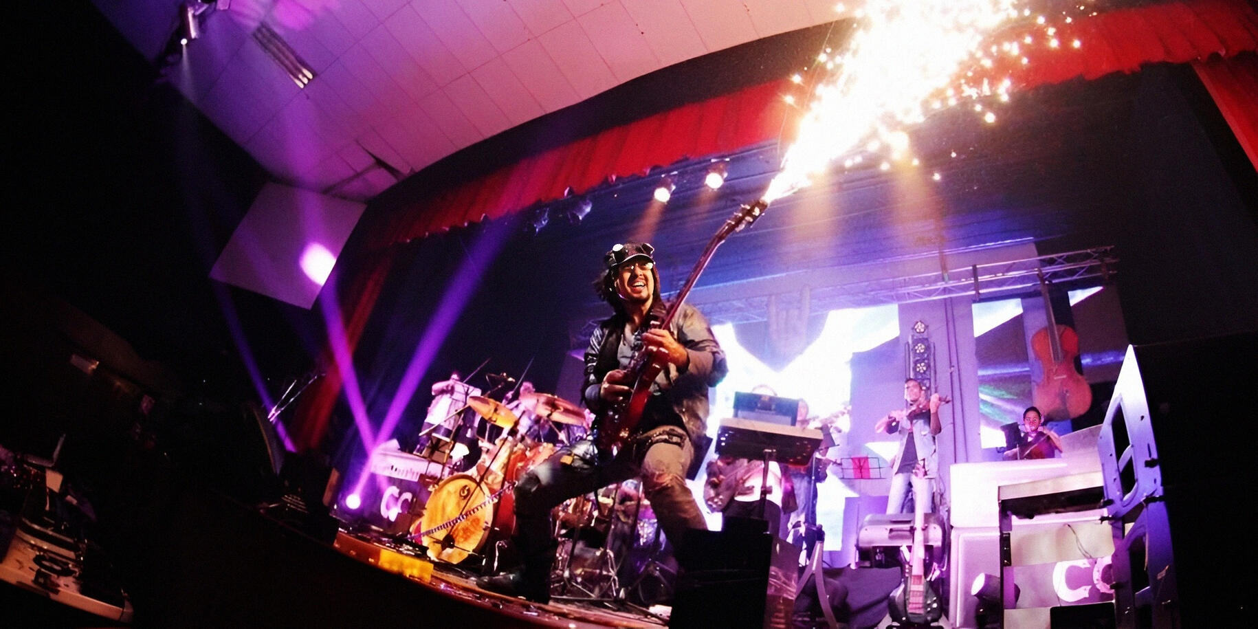 High-energy live moment Everton Vidal Azevedo performing live with an electric guitar emitting pyrotechnic sparks during a high-energy concert.
